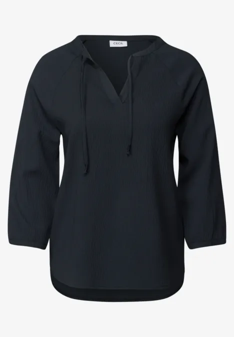 Dunkle Bluse mit langen Ärmeln und Bindeband am Kragen.